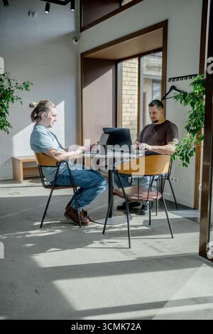 Programmers discussing over laptop working at startup. Office, business and friends together in teamwork with notebook, laptop and coffee workplace Stock Photo