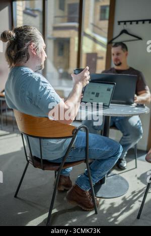 Group of cheerful young people talking and smiling during coffee break time in the office. Team of professional software developer relaxing  Stock Photo