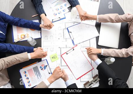 Business people with house plan holding hands at black table, top view Stock Photo