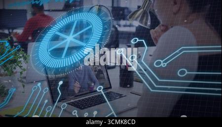 Worker resting chin on hand using laptop in office, with accessories, plant and coffee, copy space Stock Photo