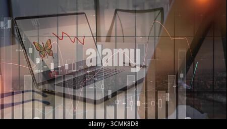 Laptop displaying butterfly icon and red trendline on conference table, with chart overlay Stock Photo