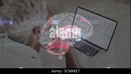 Black man in white shirt typing data on laptop at desk, holographic brain floating, phone, notebook Stock Photo