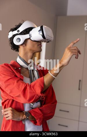Virtual reality headset displaying interface, hand pointing forward in living room Stock Photo