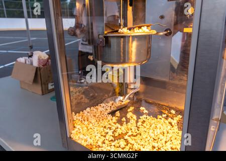 Freshly popped popcorn is being made in a popcorn machine at a sporting event, ready to be enjoyed by spectators Stock Photo