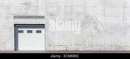 closed automatic roll-up gates on gray concrete textured wall. panoramic view on bright sunny summer day Stock Photo