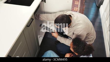 Kid, help and father with tools at house for plumbing, repair sink and support for maintenance. Above, girl and man with wrench to fix leak Stock Photo