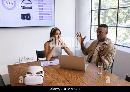 Diverse coworkers discussing design mockups with vr headset, laptop in office conference room Stock Photo