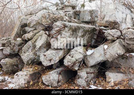 A pile of old reinforced concrete beams and pillars covered with autumn leaves and a little snow. Stock Photo