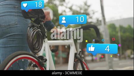 Denim-jacket cyclist viewing notifications on white bicycle with cable lock on sidewalk, copy space Stock Photo