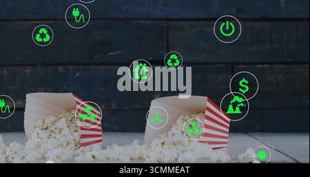 Spilling popcorn from red-and-white-striped boxes on tabletop showing green energy recycling icons Stock Photo