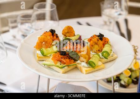 Set table for festive dinner in restaurant with plate of shrimp canapes and wine glasses. Stock Photo