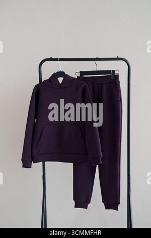 Fashionable warm dark purple cotton tracksuit on a hanger on a gray background. Cotton. Stock Photo