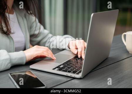 A professional woman working on her laptop outdoors. This image captures the modern concept of remote work, productivity, and a relaxed business lifes Stock Photo