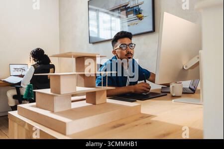 Two architecture professionals working on detailed design projects, including digital drawing and model making, in a contemporary work environment emp Stock Photo
