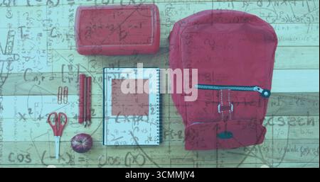 Displaying red backpack with apple and school supplies on wooden desk with math overlay, copy space Stock Photo