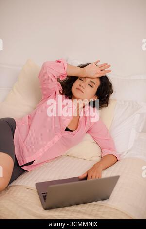 Self-employed woman working on laptop at home and having a headache Stock Photo