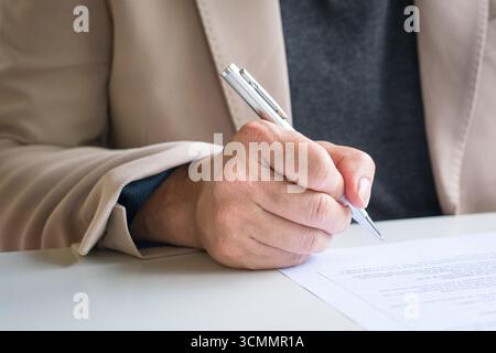 Businessman looking at document about to write or sign on it. Close up view. Stock Photo