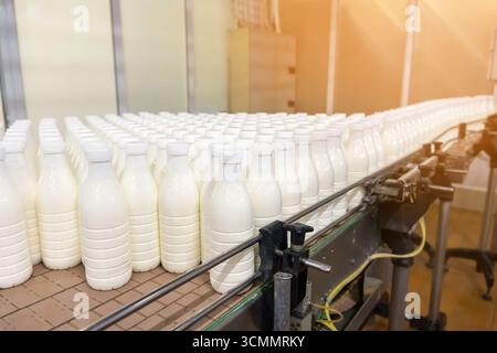 Fresh milk packaged in plastic bottles transported by conveyor system at dairy factory. Industrial equipment and production line for food and beverage Stock Photo