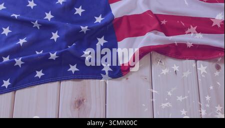 Displaying draped American flag on light wood planks, with star reflections across surface Stock Photo