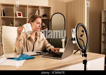 Professional woman working in modern office using laptop and recording setup Stock Photo