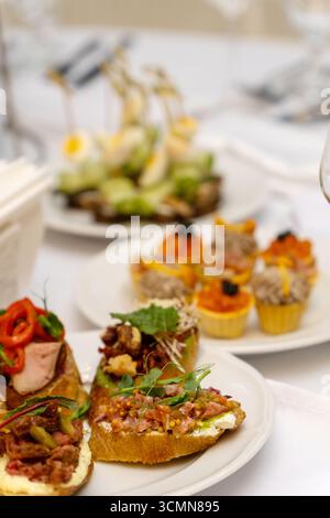 A beautifully arranged plate of assorted bruschetta, canapes, and marinated appetizers on a festive holiday table setting. Stock Photo