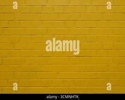 Yellow painted brick wall with regular joints and textured surface. Close-up. Copyspace. Stock Photo