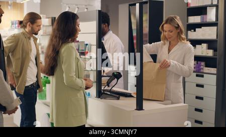 Multiracial people buying medicine in pharmacy pharmacists assisting customers order medication packing at cashier counter shopping drugstore health Stock Photo
