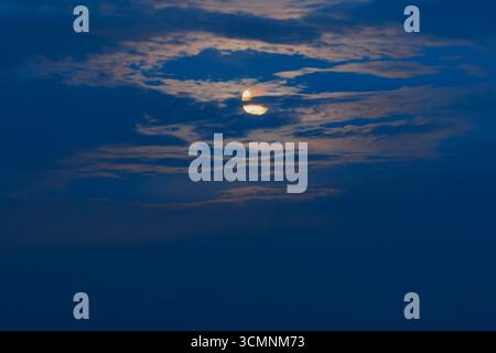 Full moon hiding behind the clouds Stock Photo