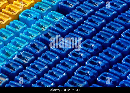 Stacked plastic jerrycans in blue, light blue, and yellow colors create a bold geometric pattern and abstract industrial background Stock Photo