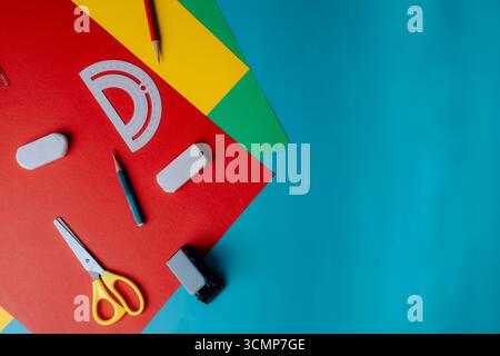 School supplies such as scissors, pencils, protractors, rulers, and erasers placed on various colored paper. Top view. Side view. Concept photo. Stock Photo
