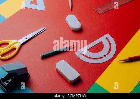 School supplies such as scissors, pencils, protractors, rulers, and erasers placed on various colored paper. Top view. Side view. Concept photo. Stock Photo