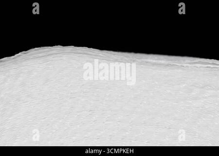 A close-up of a roll of white paper with a distinct texture and three layers of fibers. The clear details of the material create an abstract minimalis. Stock Photo