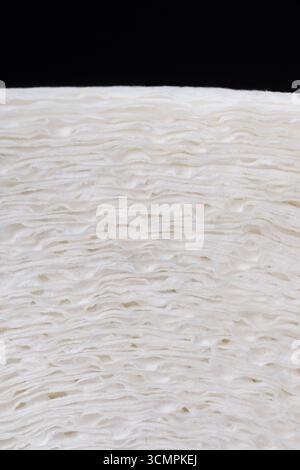 A close-up of a roll of white paper with a distinct texture and three layers of fibers. The clear details of the material create an abstract minimalis. Stock Photo