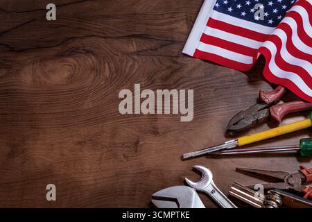 Different working tools on dark wooden background. Hand tools and the Flag of the United States of America lying on the table. View from above, close- Stock Photo