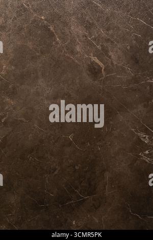 Dark brown marble surface with intricate patterns and textures displayed in natural lighting Stock Photo