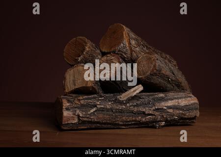 Pile of cut firewood on wooden table against dark background, closeup Stock Photo