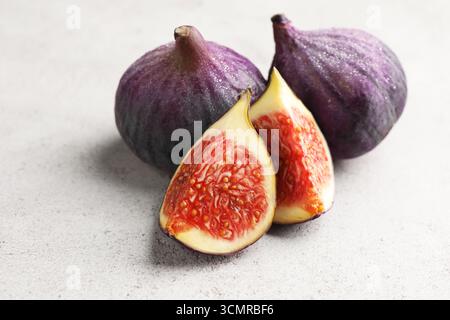 Whole and cut figs on gray textured table, closeup Stock Photo