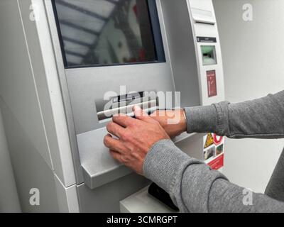 Bavaria, Germany - September 17, 2025: A man withdraws cash from an ATM with his debit card. He covertly enters the PIN or secret code *** Ein Mann hebt mit seiner EC-Karte Bargeld an einem Geldautomaten ab. Er gibt verdeckt die PIN bzw. Geheimzahl ein Stock Photo