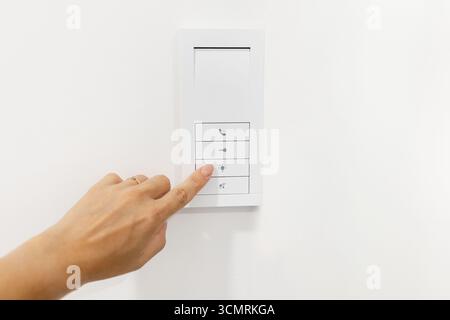 Hand pressing smart home wall control panel. Concept of modern home automation Stock Photo