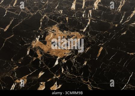 Black marble surface with intricate golden and white veining details showcases natural beauty and elegance for design purposes Stock Photo