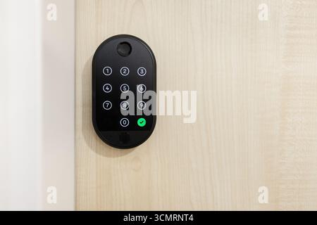 Smart lock keypad installed on wooden door. Security solution for smart homes Stock Photo