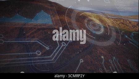 Projecting digital HUD interface hovering over brown hillside, with circuit lines and graph panel Stock Photo