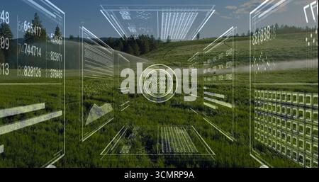 Floating circular digital interface hovering over rural hillside meadow, with numeric data panels Stock Photo