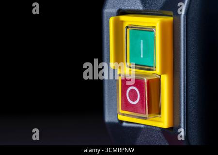 An electronic panel on an industrial machine with a green power button and a red power button. Electrical power switches on the yellow panel, close up Stock Photo
