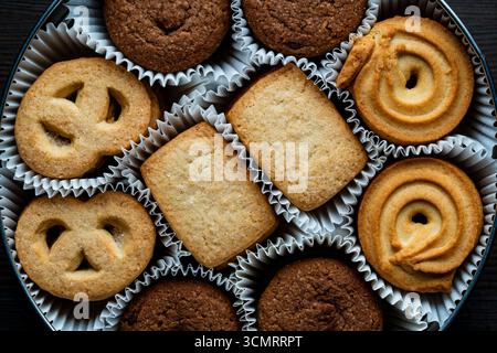Crispy crumbly shortbread cookies in a round metal box on wooden table, top view, close up Stock Photo