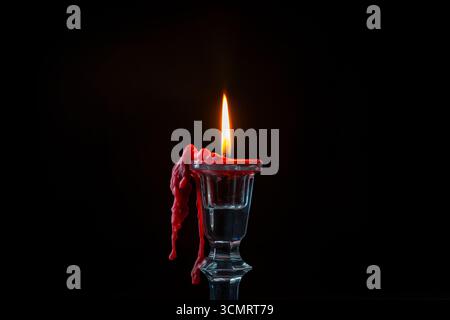 Glass candlestick with red burning candle on black background, close up Stock Photo