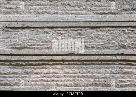 Detailed macro view of a concrete wall surface with horizontal grooves and rough texture, captured in neutral gray tones, ideal for backgrounds, archi Stock Photo
