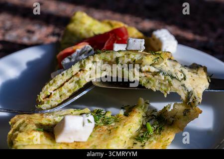 Zucchini pancakes stuffed with cheese and herbs in white plate, close up. Pie with zucchini, cheese and herbs on the table Stock Photo