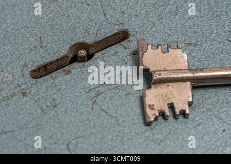 Old key is lying next to keyhole on lock Stock Photo