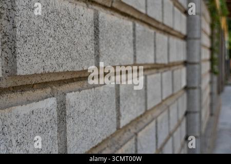 Close-up of light gray brick wall with rough texture and dark mortar joints in a running bond pattern, ideal for backgrounds, architecture, and design Stock Photo